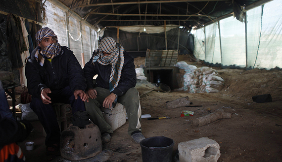 Tunnel workers sit outside a smuggling tunnel on the border between Egypt and the southern Gaza Strip